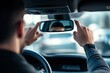 © Thanapong - Ensuring safety while driving a young professional adjusting car's rearview mirror in urban environment for optimal visibility