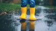 © Aysel - Feet of child in yellow rubber boots jumping over a puddle in the rain