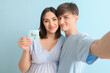 © Pixel-Shot - Young pregnant couple holding paper with word BOY on blue background