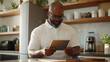 © Ольга Ничипорчук - A modern Black professional enjoys the freedom of remote work, using a tablet to navigate social media, conduct market research, and manage his thriving e-commerce business