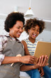 © NDABCREATIVITY - Happy african american single mother helping child with distance education. Online education