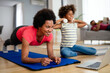 © NDABCREATIVITY - Happy young mother and daughter practicing yoga together at home, enjoying healthy lifestyle
