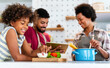 © NDABCREATIVITY - Happy african american family preparing healthy food in kitchen, having fun together on weekend