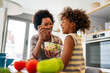 © NDABCREATIVITY - Healthy eating family and people concept. Happy mother and daughter having breakfast at home kitchen