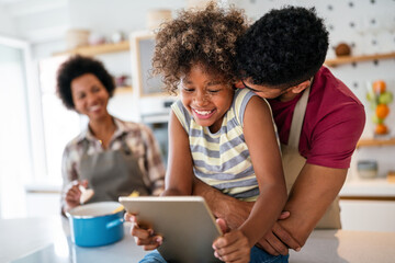 Wall Mural - Happy african family having fun with device at home. Black parents and child using digital tablet