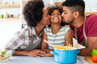 © NDABCREATIVITY - Happy african american parents and child having fun preparing healthy food in kitchen