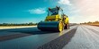© Ahmad - A robust road roller is operating on an asphalt site, laying down the surface for a new highway. The scene is presented in a landscape orientation.