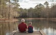 © SH Design - An old man and a young boy are sitting on a dock by a lake