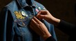 © Passion - Young adult adjusting buttons on denim jacket with embroidered patches