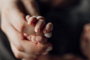 a hand holding a baby's hand. the baby's hand is small and white. concept of tenderness and love bet