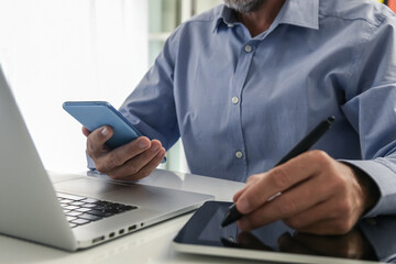 Wall Mural - Closeup man hands using smartphone, laptop and tablet. Businessman works with computer, phone, pad