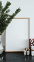 Wall Mural - Minimalist holiday mockup scene with empty wooden frame, pine branches in glass vase, and wrapped Christmas presents on dark surface against white wall background.