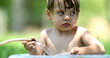© Marco - Toddler boy playing with water hose outdoors during summer day inside bucket