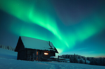 Wall Mural - old wooden cabin in snowy mountains under incredible northern lights in starry sky. christmas landsc