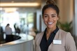 © Milos - A professional female receptionist standing in a modern office environment, radiating confidence and warmth while welcoming guests and visitors with a bright smile.