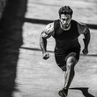 © StockUp - An intense runner strides forward, embodying speed and focus in a striking black and white setting.