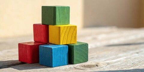 Poster - Stack of brightly colored wooden blocks arranged in a pyramid shape on a weathered wooden surface