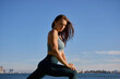 © Luis Garcia - woman stretching by the water wearing a green fitness outfit.