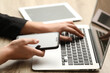 © New Africa - Businessman using laptop and smartphone at wooden table, closeup. Modern technology