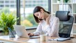 © engincan - woman working in office suffers from neck pain and holds her neck