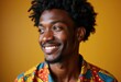 © Vibudhaart - A joyful young Black man with an afro smiles, wearing a vibrant patterned shirt against a warm yellow background.