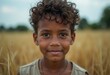 © Vibudhaart - A young boy with curly hair smiles gently in a golden field.