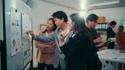 Wall Mural - Experienced corporate team collaborating during strategic meeting, analyzing performance charts and graphs on whiteboard while sharing innovative business insights