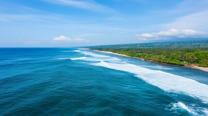 Wall Mural - Serene ocean waves crashing on a tropical beach. Lush green tropical vegetation meets a wide, sandy beach on the shoreline.