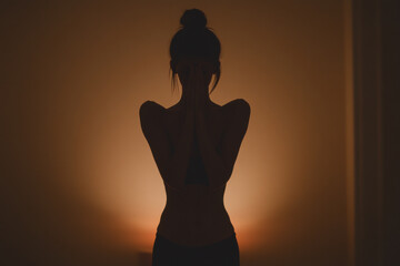 Wall Mural - A woman is standing in a dimly lit room with her back to the camera