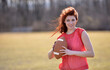 © aspenphoto - Beautiful young Caucasian female football (American) player in red jersey smiling while holding football - red hair