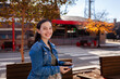 © Austockphoto - Teen girl with big smile holding device while outside on main street of country town