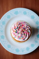 Canvas Print - Tasty Cupcake with Pink Frosting and Blue Sprinkles on a White Plate (