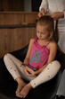 © Sabineyro - the girl sits in a chair and watches cartoons on her phone. gadgets and children