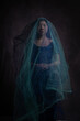 © Milou Dirks - dark artistic studio portrait of an asian woman in a blue dress covered by thin fabric