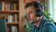 © GOPINATH - focused man wearing headphones working in a cozy home office with bookshelves in the background.