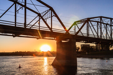 Wall Mural - A bridge over a river with the sun setting in the background