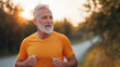 © NaphakStudio - senior man jogging in orange shirt during sunset, showcasing vitality and health. serene background enhances feeling of outdoor exercise.