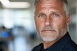 © Milos - A male police officer with striking blue eyes and a serious expression shows confidence, ready to protect and serve in a modern and professional environment.