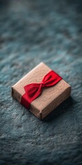 Wall Mural - A small, wrapped gift box tied with a red ribbon on a textured surface.