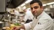 © milenialdesastudio - Confident male chef in a busy restaurant kitchen, preparing food.