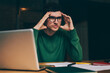 © BullRun - Serious male entrepreneur pondering on startup project sitting at desktop with papers and laptop, puzzled young man student in eyewear thinking about course work and planning study process indoors