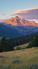 Wall Mural - A mountain range with a large mountain in the background. The mountain is covered in snow. The sky is cloudy and the sun is setting