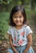 © Julija - A cheerful girl in a floral shirt sits on a path surrounded by lush greenery in Thailand. Her bright smile reflects the joy of playing outdoors and exploring nature. Generative AI