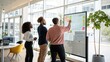 © Khalis Mustapha - A team of employees brainstorming with colored markers on a glass board in a modern and collaborative bright workspace environment.