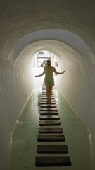 Wall Mural - Woman walking on stepping stones in water tunnel at lagomar lanzarote canary islands wearing sunglasses and summer outfit