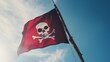 © Topuria Design - Red pirate flag waving high against a clear blue sky. A striking pirate flag with a skull and crossbones sign flies in the wind.