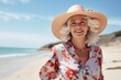 © Igor - Portrait of beautiful senior woman in hat and floral dress on the beach