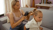 © Krakenimages.com - Woman brushing child's hair on a sofa in a cozy living room, highlighting their bond and capturing a tender family moment.