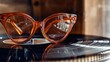 © Tadeusz - Stylish orange cat-eye glasses resting on a classic vinyl record.
