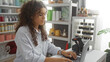© Krakenimages.com - Woman working in a decor shop typing on a laptop amidst a well-organized and stylish interior with shelves of home decor items